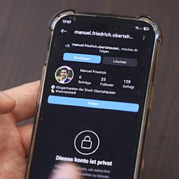 Foto: Smartphone in einer Hand. Darauf ist ein 'privat' geschaltetes Social Media Profil zu erkennen mit Bild und Namen einer Person.