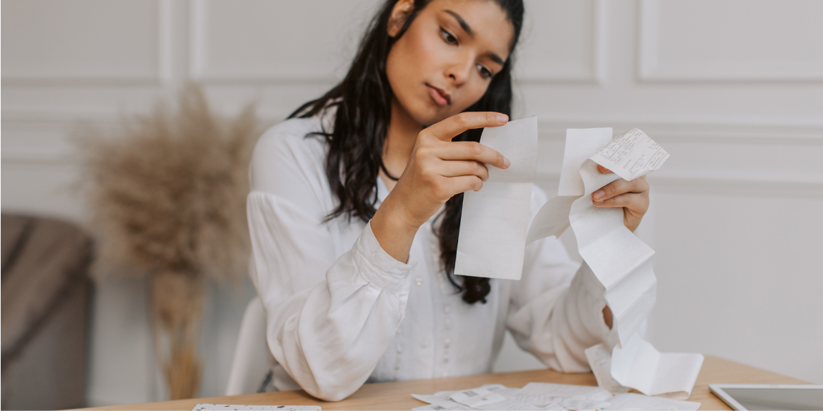 Woman checking cash receipts and expenses at home table