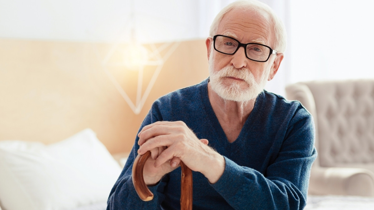 Elderly pensioner sitting thoughtfully at home reflecting on financial security