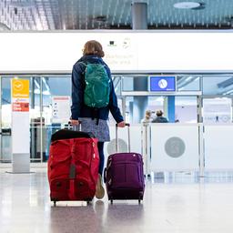 Ein Fluggast mit Koffern am Flughafen - A traveler with luggage represents the journey abroad