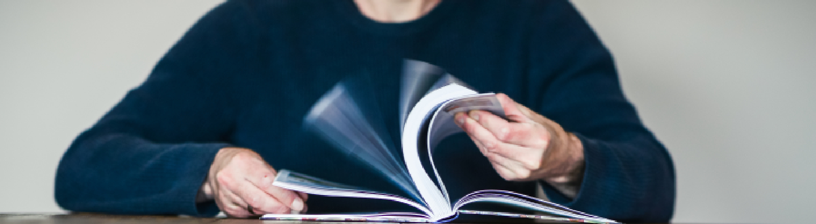 Ein Mann blättert in einem Buch. Die Szene symbolisiert die Suche nach Sinn und Erkenntnis.