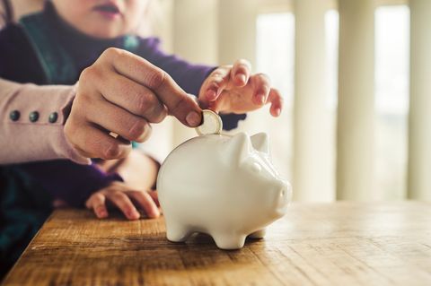 An older hand and a child's hand over money, symbolizing income and career choices