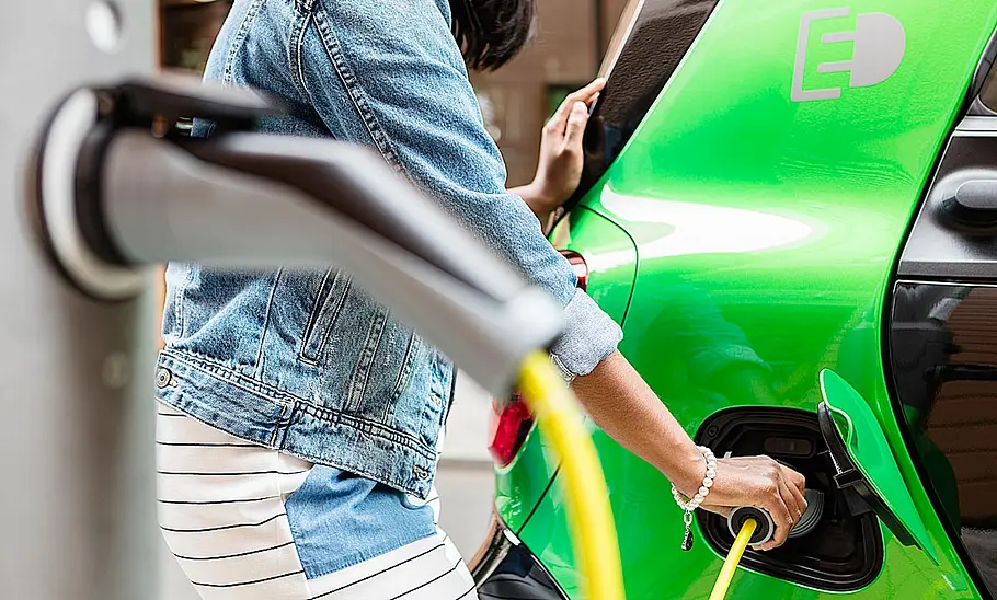A woman plugging in her electric car to charge.