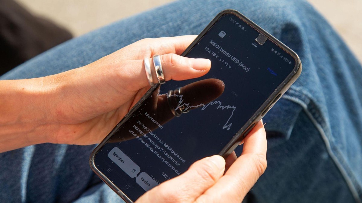 Eine Frau sieht sich einen ETF-Kurs auf einem Handy an