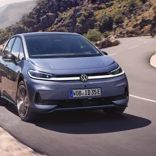 Ein blauer VW ID.3 Neo fährt auf einer kurvigen Bergstraße.